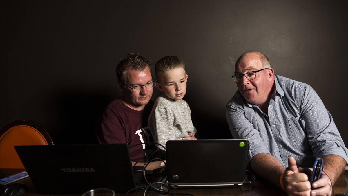 SIT AND WAIT:  Group F candidate Kenrick Winchester, his nephew Riley Element 10, and fellow candidate Tony Wood check election results as they roll in. Photo: Jamila Toderas