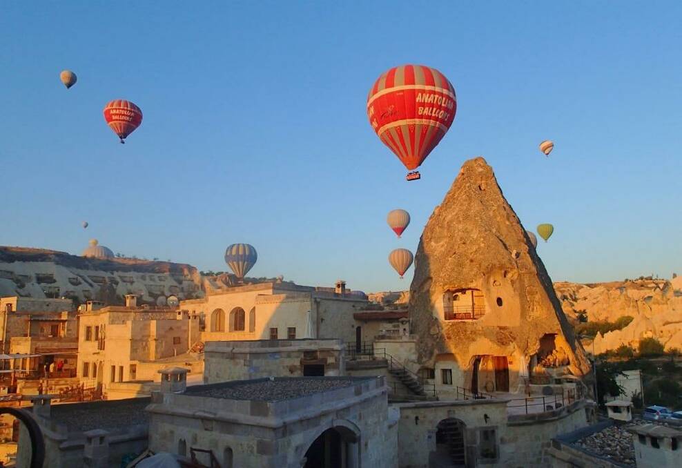 This photo was taken at dawn from our hotel balcony in Goreme, Turkey in 
August 2014.  We were given a cup of coffee, and were rugged up against the cold.  Our room was in the fairy chimney in the picture.  Some of the balloons were so close we waved to the people in the baskets.  There were hundreds of balloons.  It was an amazing sight. The early morning light was beautiful.  One of the highlights of our holiday in Turkey.
 Photo: Ann Thorburn
