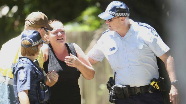 Police try to comfort a woman in Murray Street, Manoora, outside the Cairns house where the bodies of eight children were found. Photo: Dominic Chaplin 