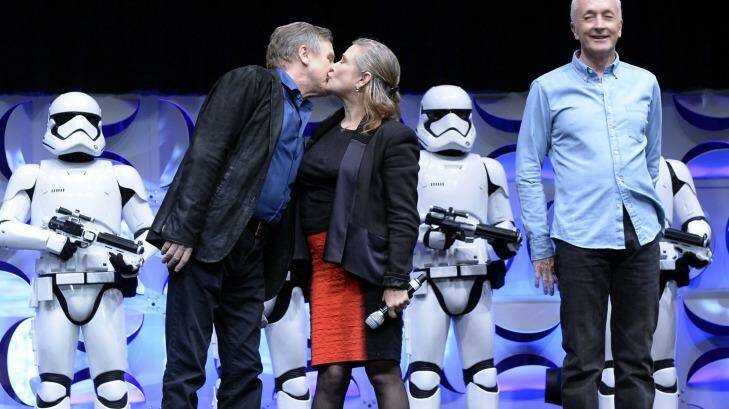 Cast members of the original Star Wars film Mark Hamill (L) and Carrie Fisher (C) kiss as Anthony Daniels looks on during the kick-off event of Disney's Star Wars Celebration 2015. Photo: Kevork Djansezian/Getty Images 