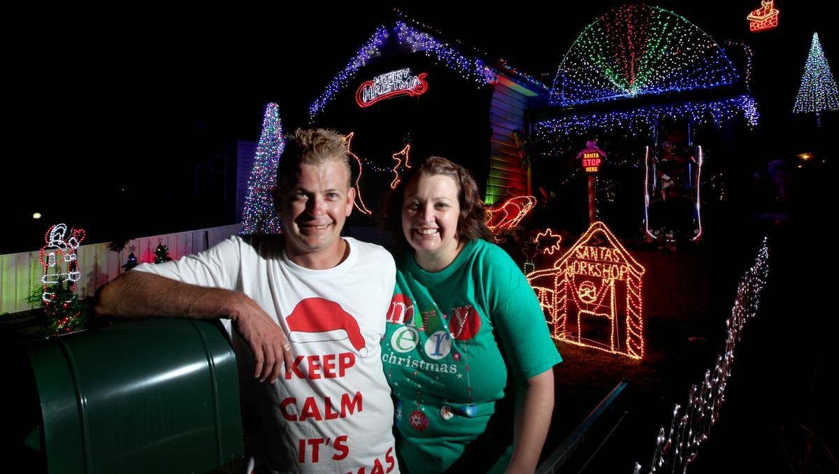 Aaren Bower and wife Melissa standing in front of their decorated house in Newcastle. Photo: Ryan Osland/The Herald