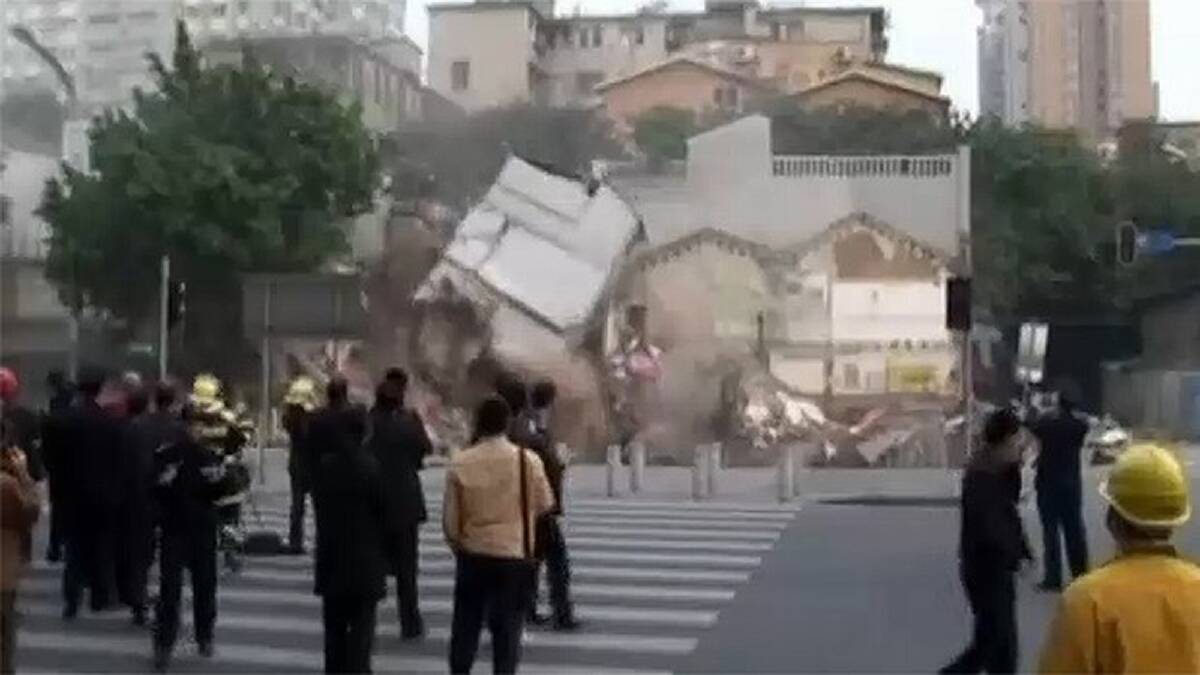 A three-storey building next door also collapses into the giant hole as bystanders watch. Photo: ITN screengrab