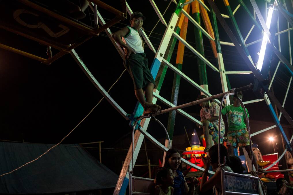 Ferris wheel attendants wait for customers before spinning the wheel at a rural carnival in South Dagon Township on February 14, 2013 in Yangon, Burma. Photo by Chris McGrath/Getty Images