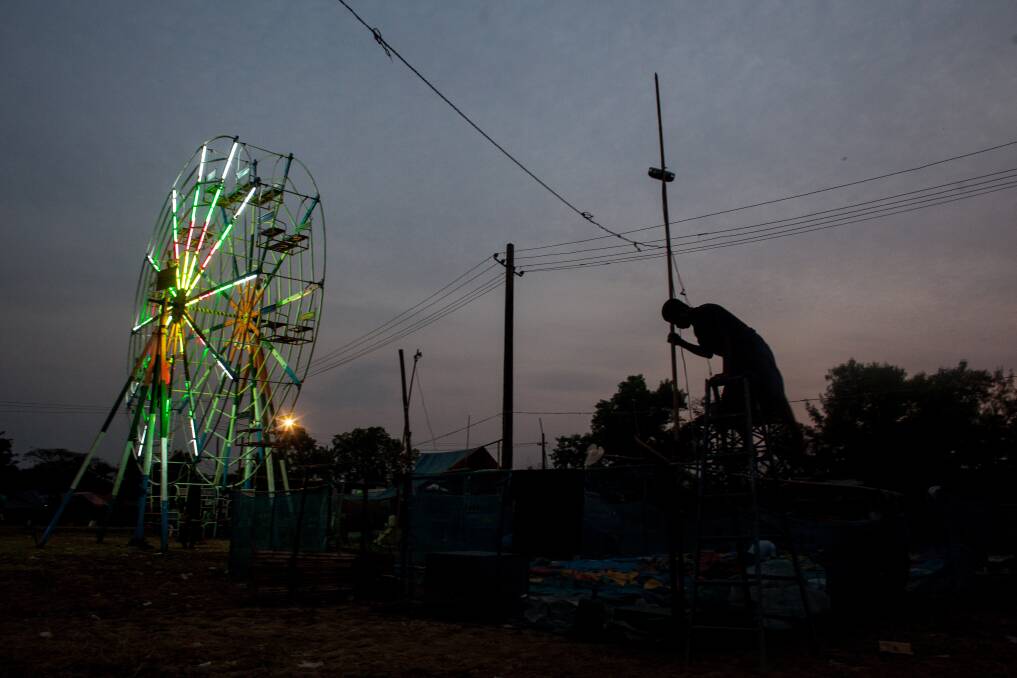 A man hooks up power at a traveling carnival site at South Dagon Township on February 14, 2013 in Yangon, Burma. Photo: Chris McGrath/Getty Images