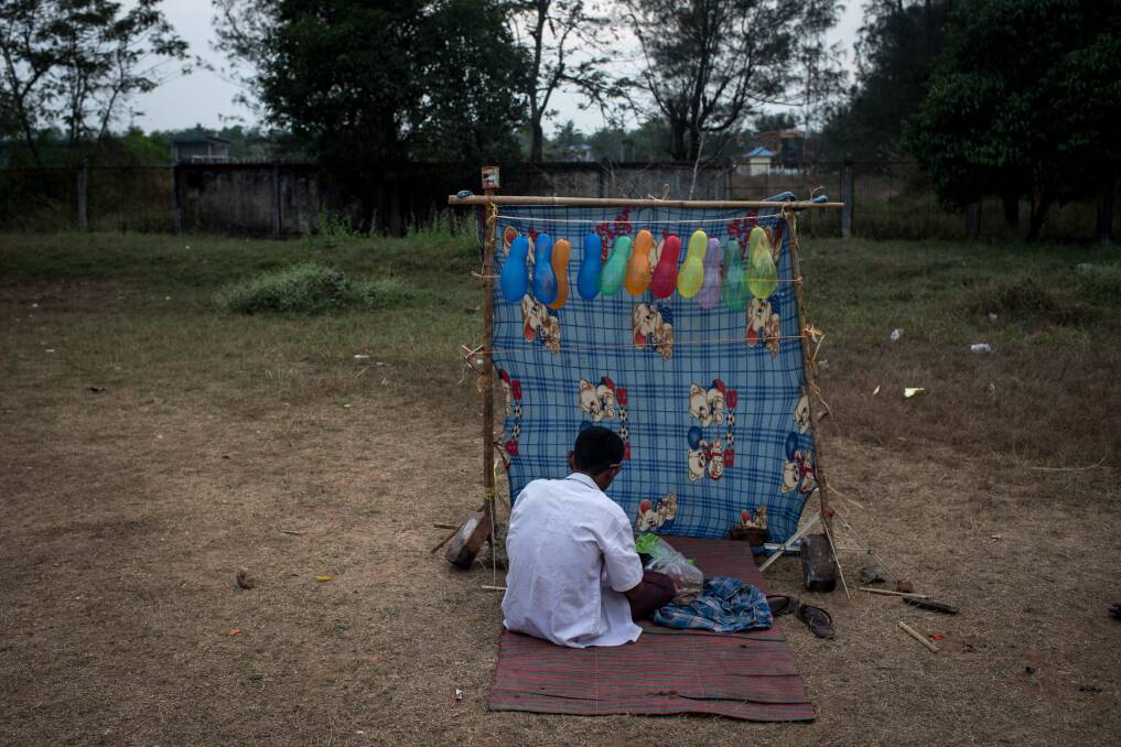 A carnival worker prepares a rubber band, balloon popping stand, prior to the start of the rural carnival in South Dagon Township on February 14, 2013 in Yangon, Burma. Photo by Chris McGrath/Getty Images