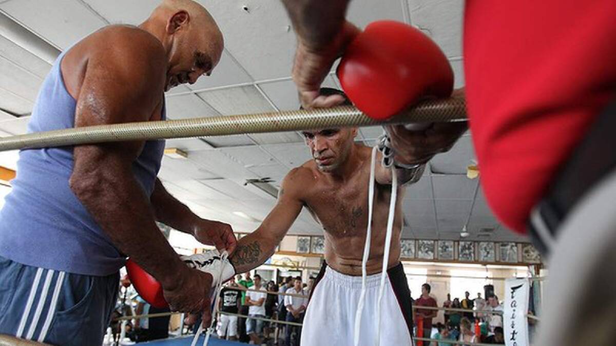 Mundine's trainers assist with getting his gloves on. Photo: Anthony Johnson