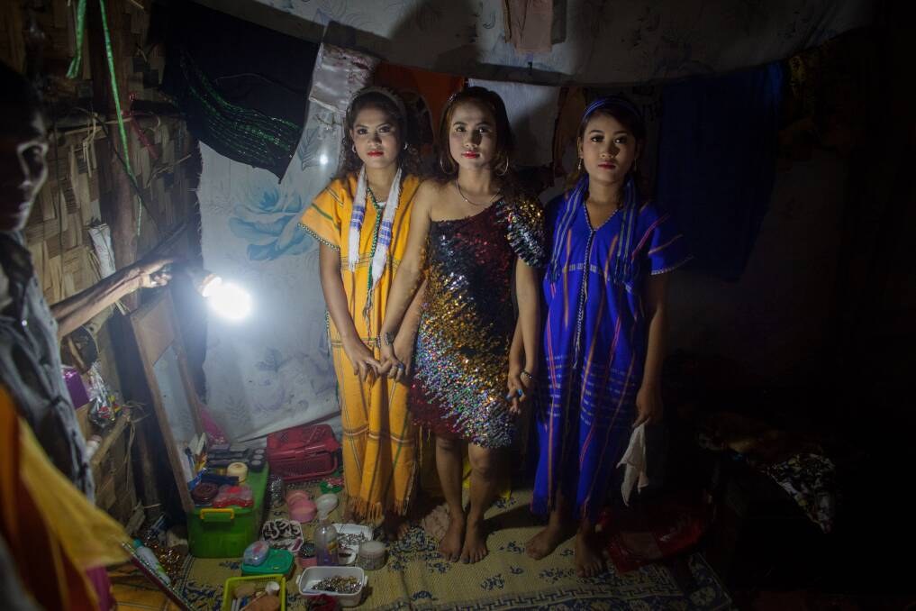 A woman holds a light as she poses three performers in traditional dress from the Phoe Chit Naing Orchestra band for the photographer backstage before the show at a carnival in South Dagon Township on February 14, 2013 in Yangon, Burma. Photo: Chris McGrath/Getty Images
