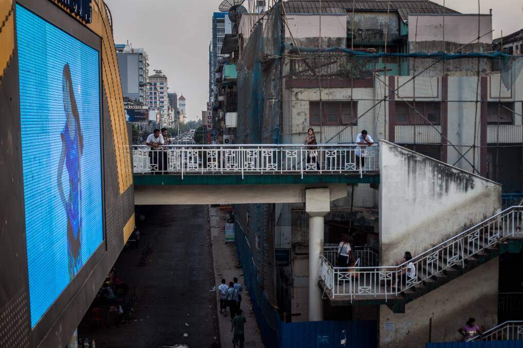People watch an electronic billboard from an overpass on February 10, 2013 in Yangon, Burma. Photo Chris McGrath/Getty Images