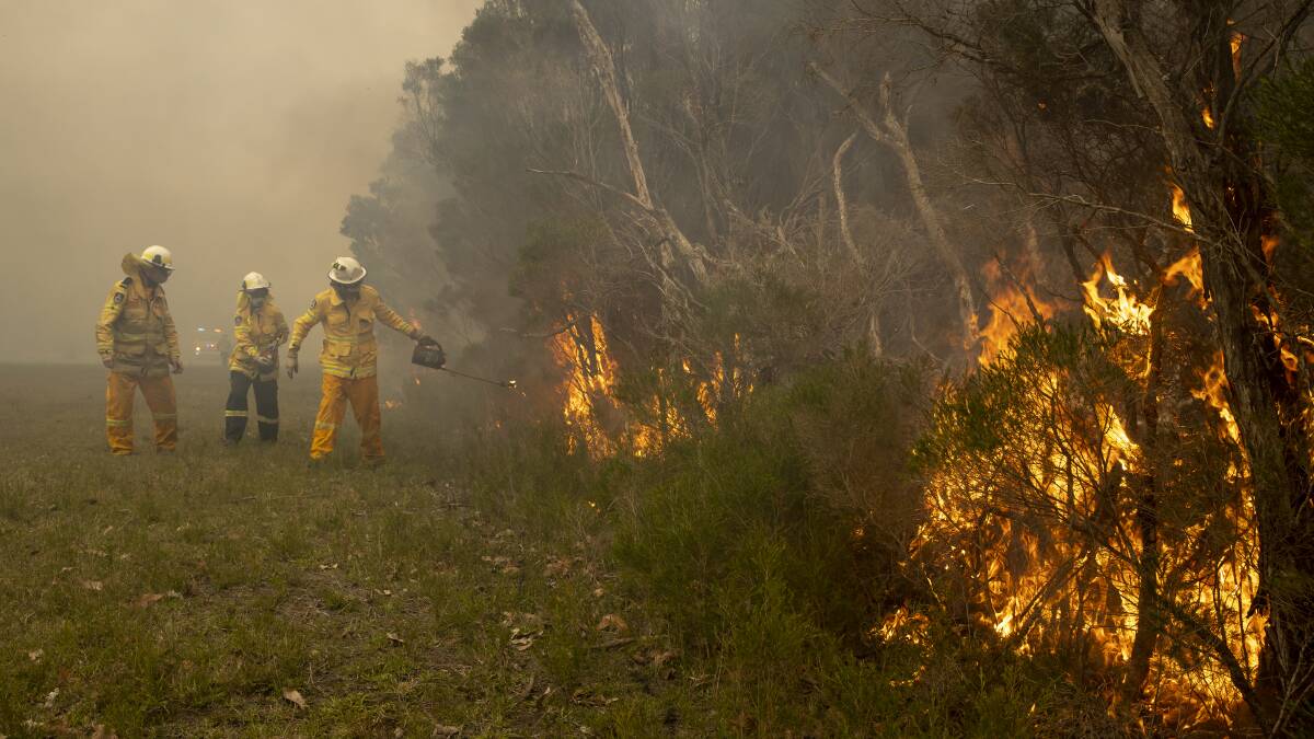 Firefighters conduct a controlled burn in Bawley Point, a day after a bushfire swept through the area. Picture: Sitthixay Ditthavong