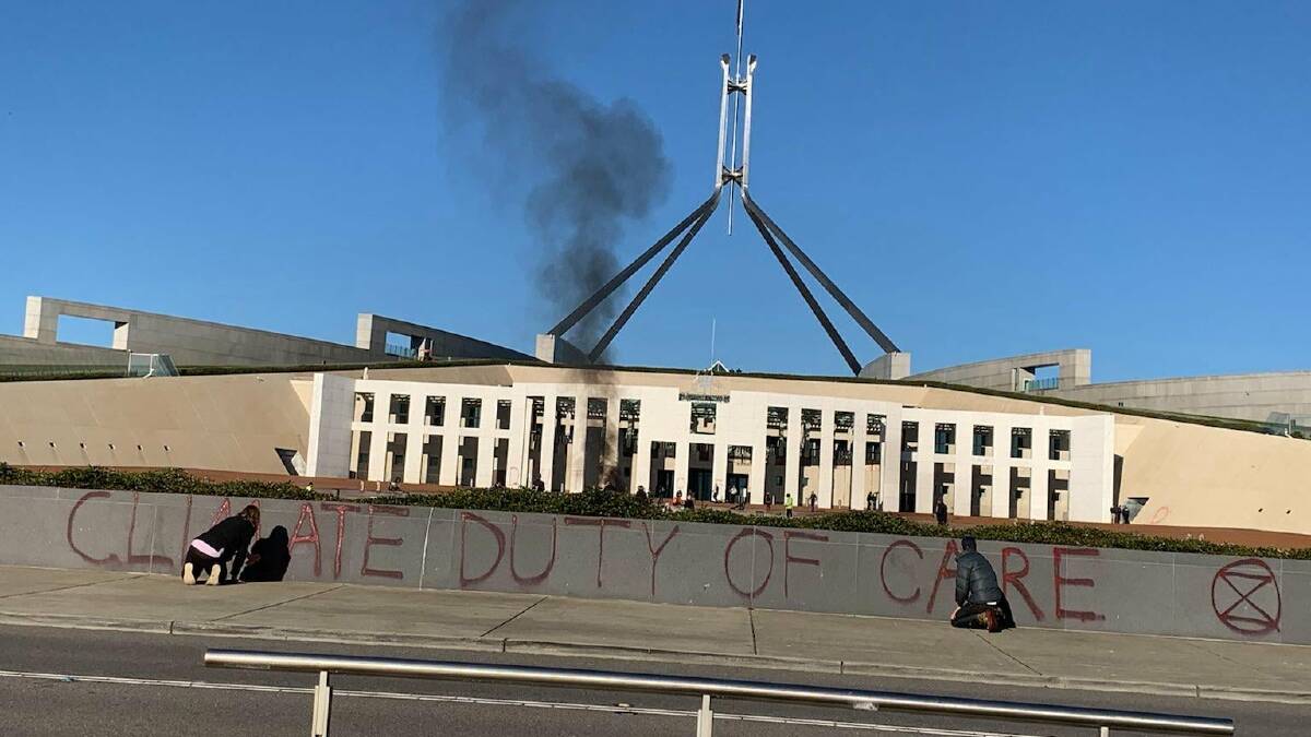 Climate Duty of Care has been painted on the concrete fence of Parliament House. Picture: Supplied.