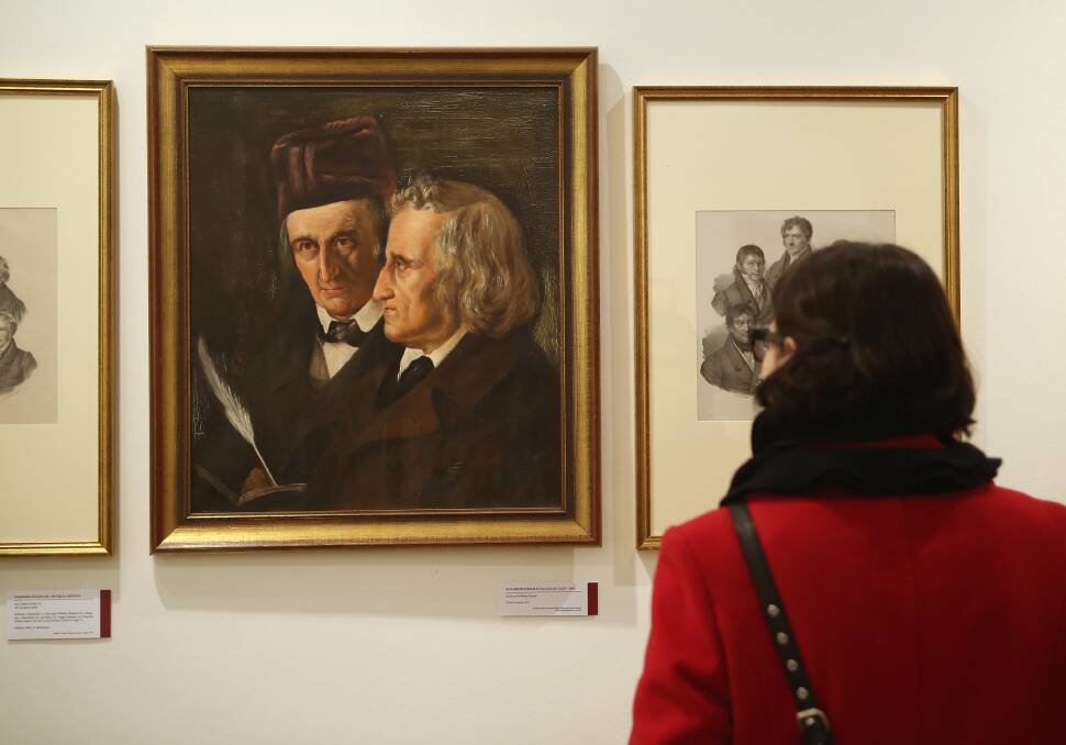 A museum administration employee, at the request of the photographer, looks at a painting of brothers Jacob and Wilhelm Grimm at the Grimm Brothers Museum in Kassel, Germany. Photo by Sean Gallup/Getty Images